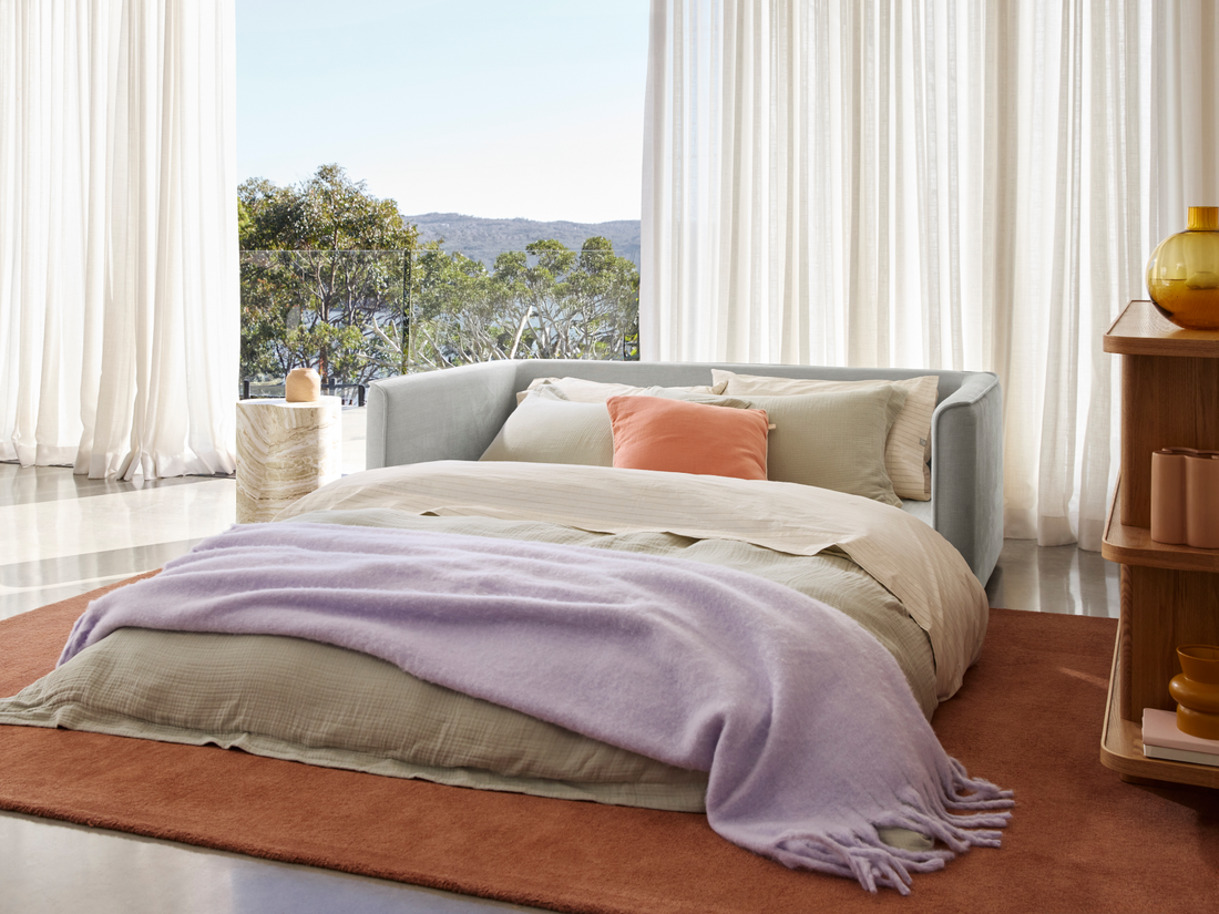 an open sofa bed with sheets and pillows