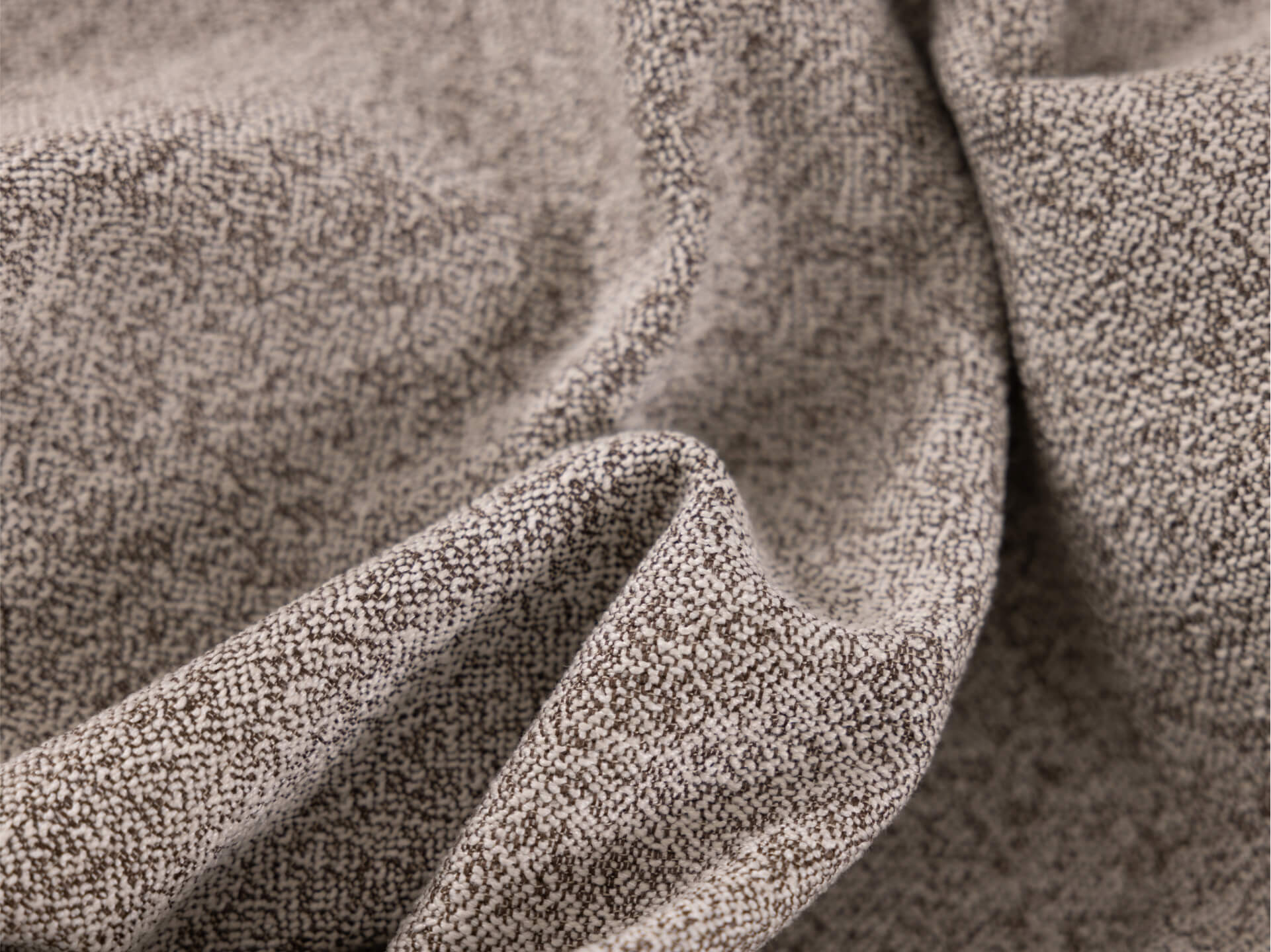 Close-up of textured fabric revealing a light beige background with tiny brown speckles, creating a subtle, patterned weave.